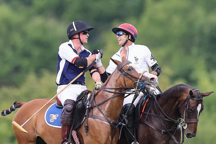 Polo players laughing together on horseback during match